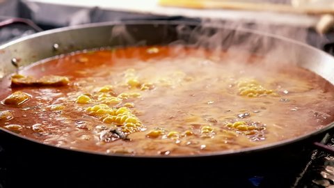 Close up slow motion video of delicious spanish traditional cuisine seafood paella boiling in huge pan, food in motion