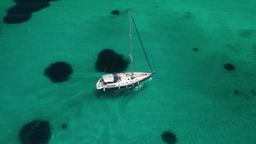 Aerial drone video of sail boat cruising near famous Psarou emerald beach in Mykonos island, Cyclades, Greece