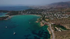 Aerial drone bird's eye panoramic video of famous celebrity sandy beach and peninsula of Astir or Asteras in south Athens riviera with turquoise clear sea, Vouliagmeni, Greece