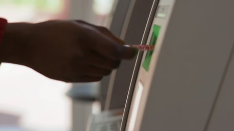 Close-up view of black hand inserting a credit card into an ATM machine. African american man using a cash machine withdrawing money in a bank.