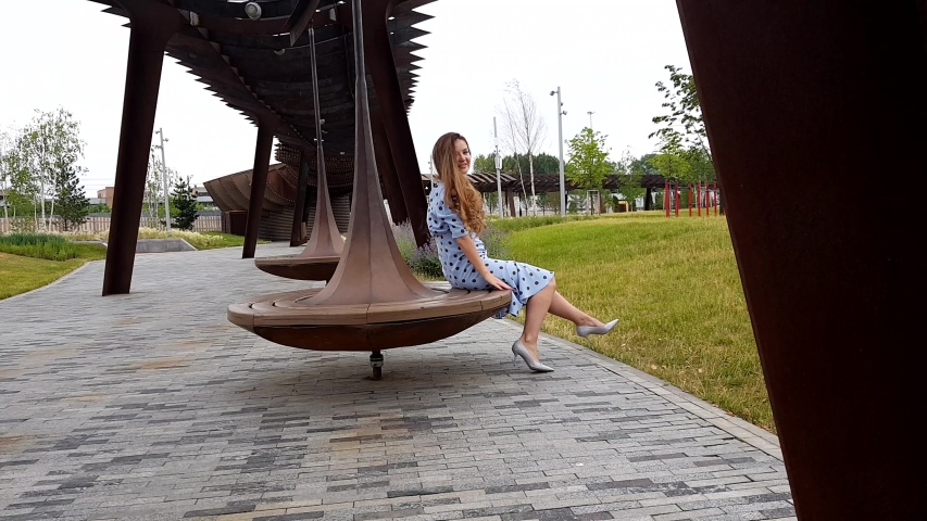 Pretty adult woman Spinning On Bench In Park