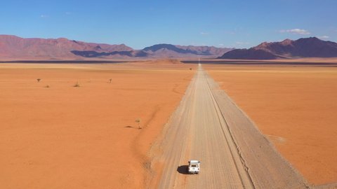 NAMIBIA - CIRCA 2018 - High aerial over a Toyota safari vehicle heading across the flat, barren Namib Desert in Namibia.