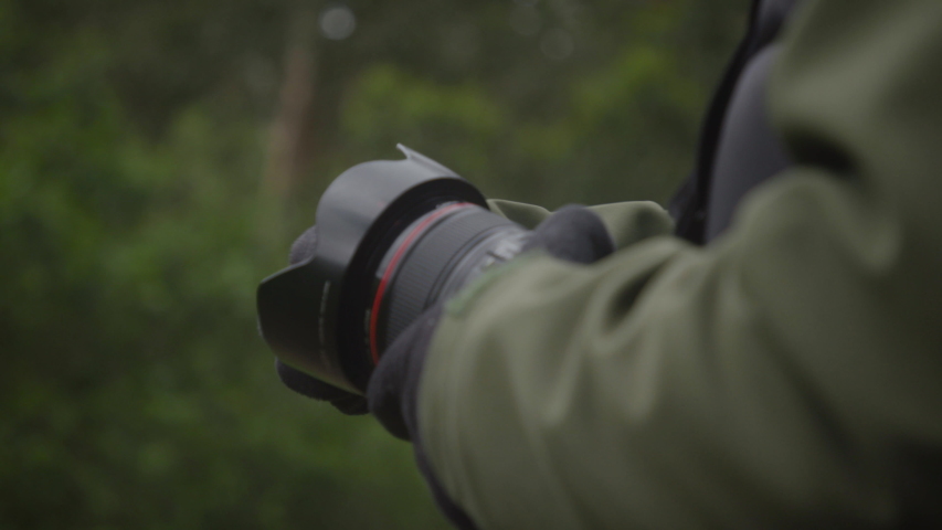 Photographer close up hands holding camera with gloves on during a cold day outside in the forest.  Shot on a Canon C200 in 4K in slow motion.