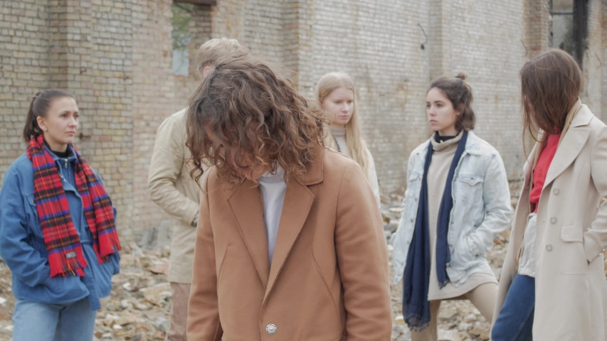 Curly woman straightens hair among a group of young people in the ruins and leaves. Youth doing a theater sketch among a collapsed brick building Royalty-Free Stock Footage #1031473943