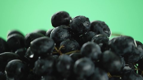 in the video we see the grapes, water pour from the top then stops with drops, close-up, green background