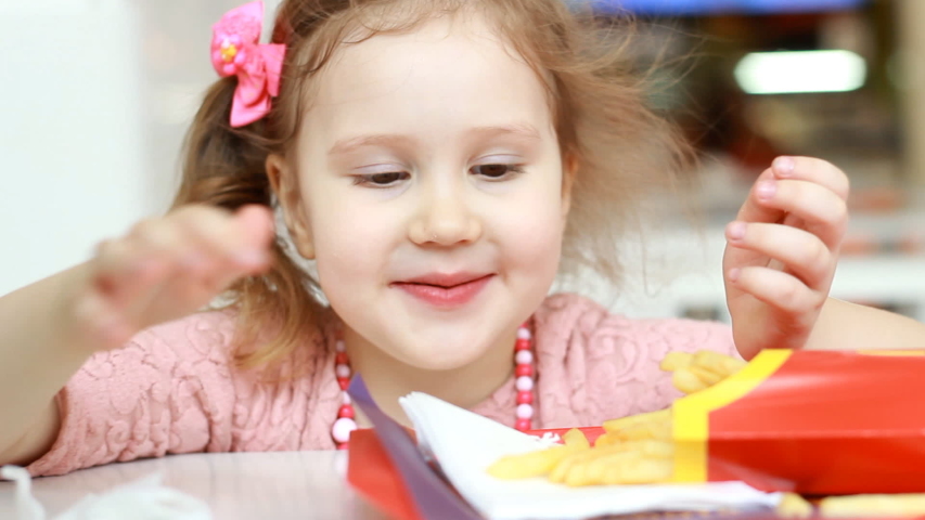 Child girl eating fast food french fries in a cafe. Portrait closeup Royalty-Free Stock Footage #1031489870