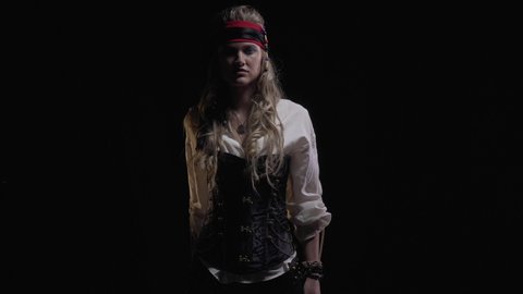 Blonde woman in pirate clothes is standing in the dark with a sword, 4k