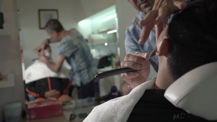 Barber shaves a man with a straight razor | Shutterstock HD Video #1031511878