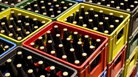 Countless colorful beer crates stacked in an outdoor warehouse on a sunny day seen from a top view. The camera moves sideways in an endless, seamless looping animation. Fresh beverage storage.
