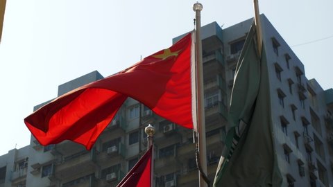 The outside. Against the background of gray buildings, the red flag of China and the green flag of Macau flutter in the wind. It's a nasty day.