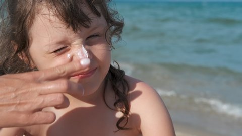 Sun protection cream. Mother to apply sunscreen on the face of the child.