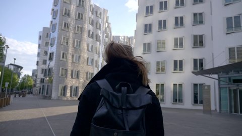 Dusseldorf, Germany - May 10, 2019: Young woman visiting the Neuer Zollhof in Media Harbor, Dusseldorf, Germany. This building was designed by Frank O. Gehry and completed in 1998.