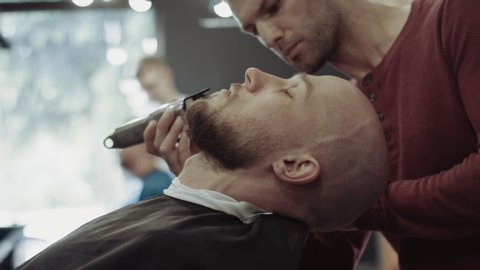 Barber cleaning clients neck with brush at barber shop.  Barber finishes the work and clean a beard of a customer. 