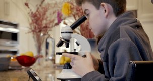 Man and young teenage boy look through a microscope while using a mobile phone as a learning tool