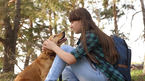 beautiful girl travels with pet. tourist girl in forest on halt with dog. mistress plays with hunting hound. mistress caresses dog. Happy woman breeder dog walks with dog. Traveler with backpack