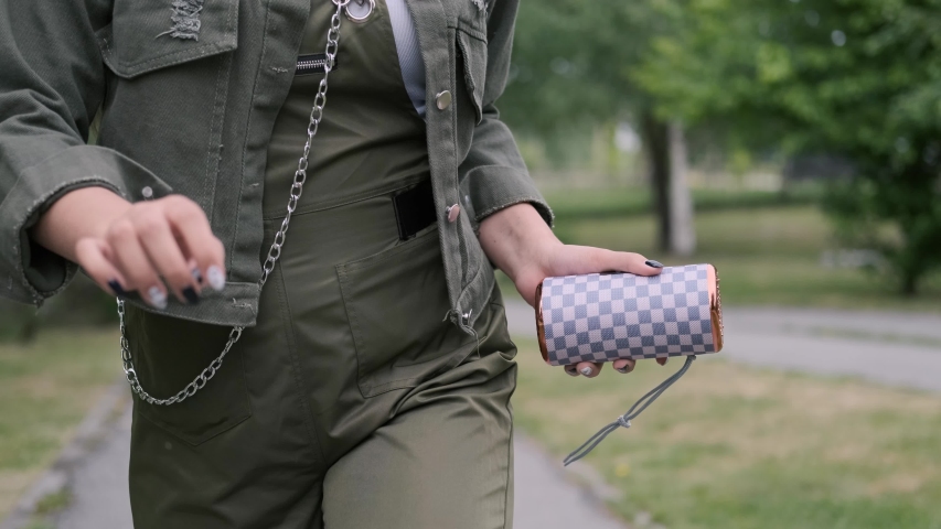Hipster girl in good mood walks down the street and dances listening to music using a portable speaker