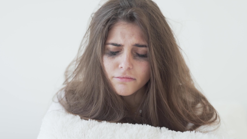 Sad girl crying on her bed, mascara running down her face