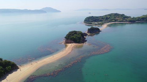 Flying under sunny sky above the Angel Road, a tidal sandbar (shoal) connecting 3 beautiful offshore islets to Shodoshima Island in Seto Inland Sea and a tourist attraction in Tonosho, Kagawa, japan
