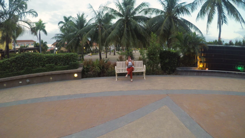 Young Beautiful Women Sitting in the Bench Holding a Cellphone