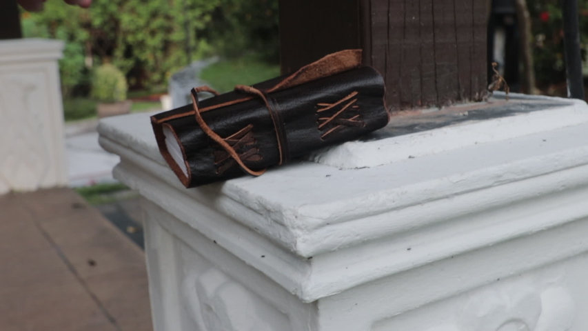 Close shot of woman reaching for mysterious leather bound book, slow motion