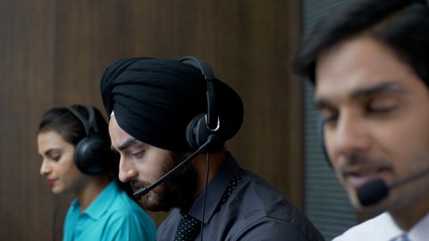 Active young Indian executives wearing headsets while working - Call center support staff in night shift