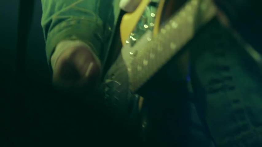 Close up of an electric guitar being played during a concert. Dim venue lighting shines on the guitar. View of artists hands strumming and playing a song for an audience. Grunge, festival scene.