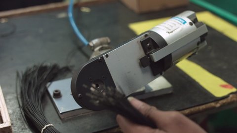 Close Up shot of a worker crimping and thimbling electrical wire with capacitor in a semi automated machine