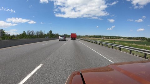 Barrie, Ontario, Canada June 2019 Driving plate POV highway with car and truck traffic and blue sky