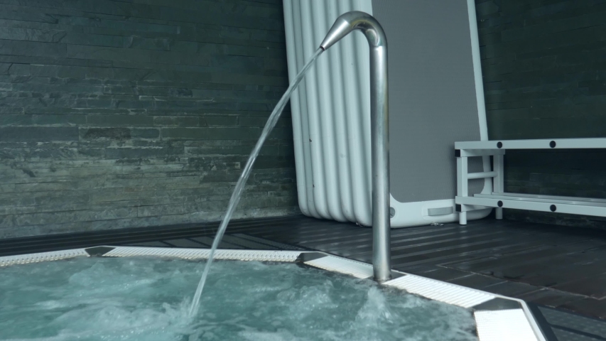 A man wearing swimming trunks washes himself in a hot-tub