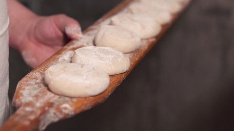 The baker puts the dough in the oven. Slow motion. Close up .
