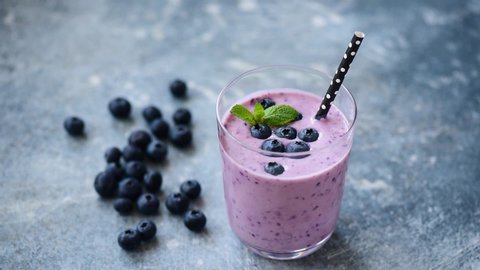 Purple blueberry acai smoothie in glass with drinking straw, overview. Healthy food and dieting concept