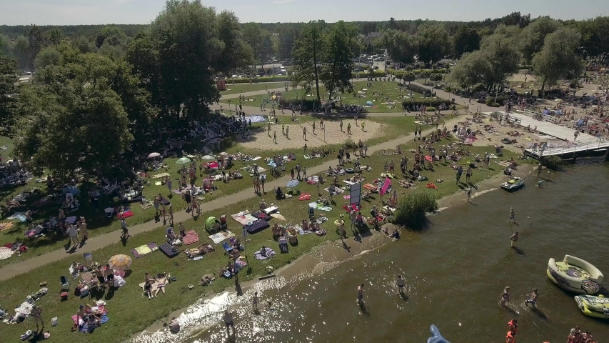 4K. Top view People swim and sunbathe on a beautiful beach on a sunny day. Summer vacation sunbathing. Aerial view People swim and sunbathe under umbrellas on a sunny summer day.