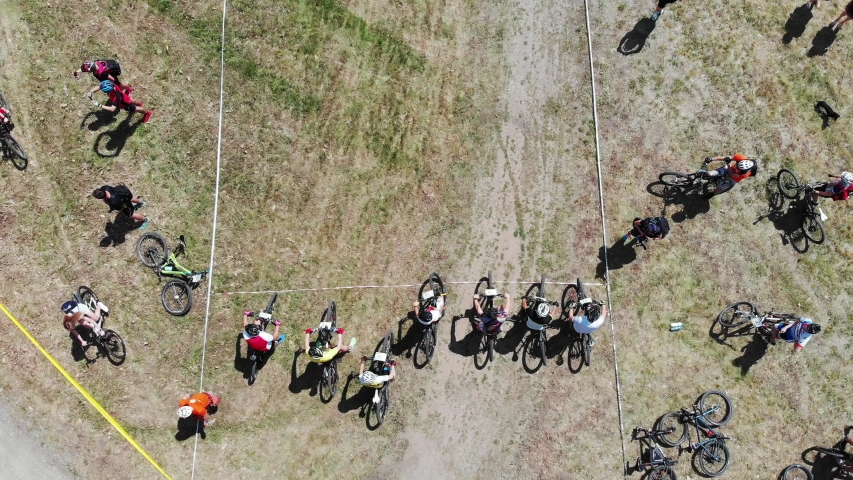 Close-up drone view of sportive strong male cyclists preparing for race at start line in city park