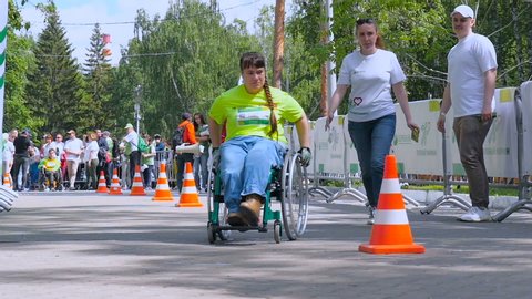 Charity marathon by Sberbank June 1, 2019, Russia, Yekaterinburg: A woman in a wheelchair participates in a marathon and overcomes obstacles. City Marathon Race.  Slow motion
