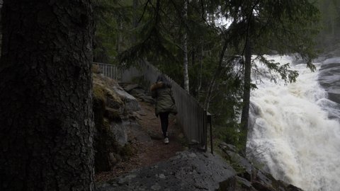 Big waterfall and a girl who walks beside it.