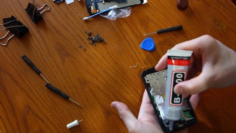 Technician or engineer disassembling components broken smartphone for repair or replace new smartphone screen on wooden desk