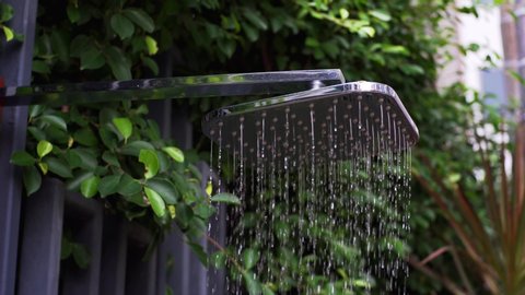 Close view of chrome shower head in the garden with water running from it