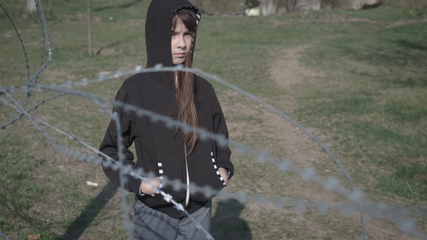 A child behind barbed wire. Children in a refugee camp. Childhood without war.