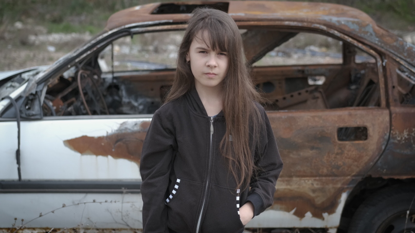The child shows a stop sign. Sad girl in slums shows stop gesture.
