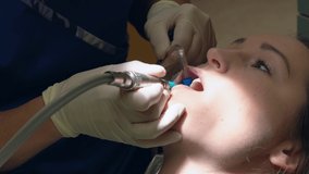 This close up video shows a caucasian woman getting her teeth cleaned and polished by a dentist.