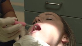 This close up video shows a caucasian woman getting her teeth cleaned by a dentist.