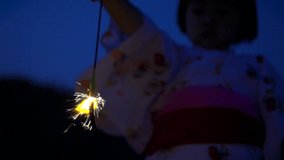 Children playing hand-held fireworks  near river