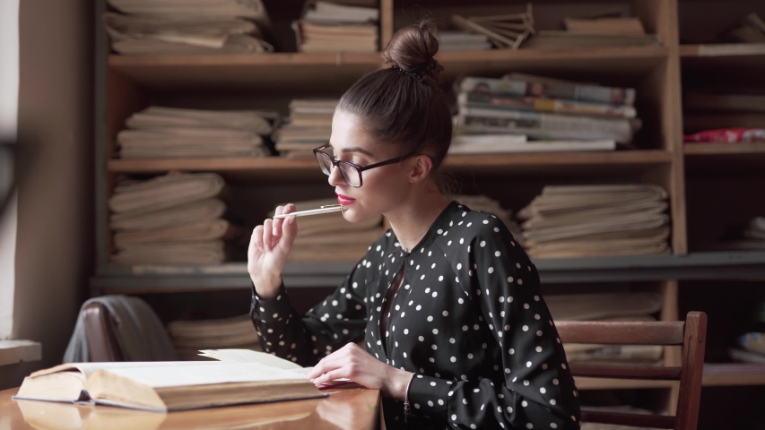 Caucasian woman taking notes in a notebook while studying in a libraray