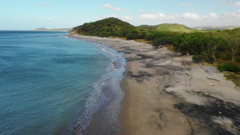 Aerial Forward: Tree Covered, Hilly Shoreline By Ocean Waves - El Gigante, Nicaragua