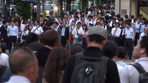 SHINJUKU, TOKYO, JAPAN - CIRCA JUNE 2019 : View of crowd of people walking down the street in busy rush hour. Many commuter walking to the train station after work. Shot in early evening.