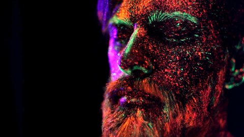 Concept. Portrait of a bearded man. The man is painted in ultraviolet powder