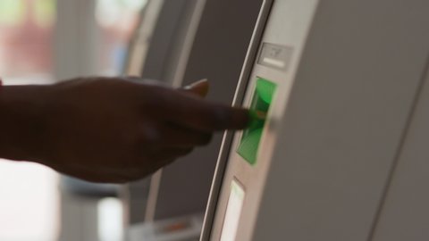 Close-up view of black hand inserting a credit card into an ATM machine. African american man using a cash machine withdrawing money in a bank.