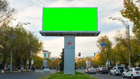 4K TIME LAPSE video.Advertising billboard with green screen with traffic cars and people against the background of the autumn landscape with moving white clouds.Day becomes night.The camera moves away
