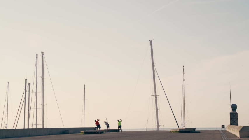 People doing sport in the port of Barcelona. Morning training, stretching and physical movements outdoor. Yacht