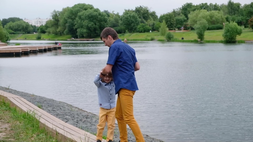 Young charming father spinning his happy son at beautiful place by the river